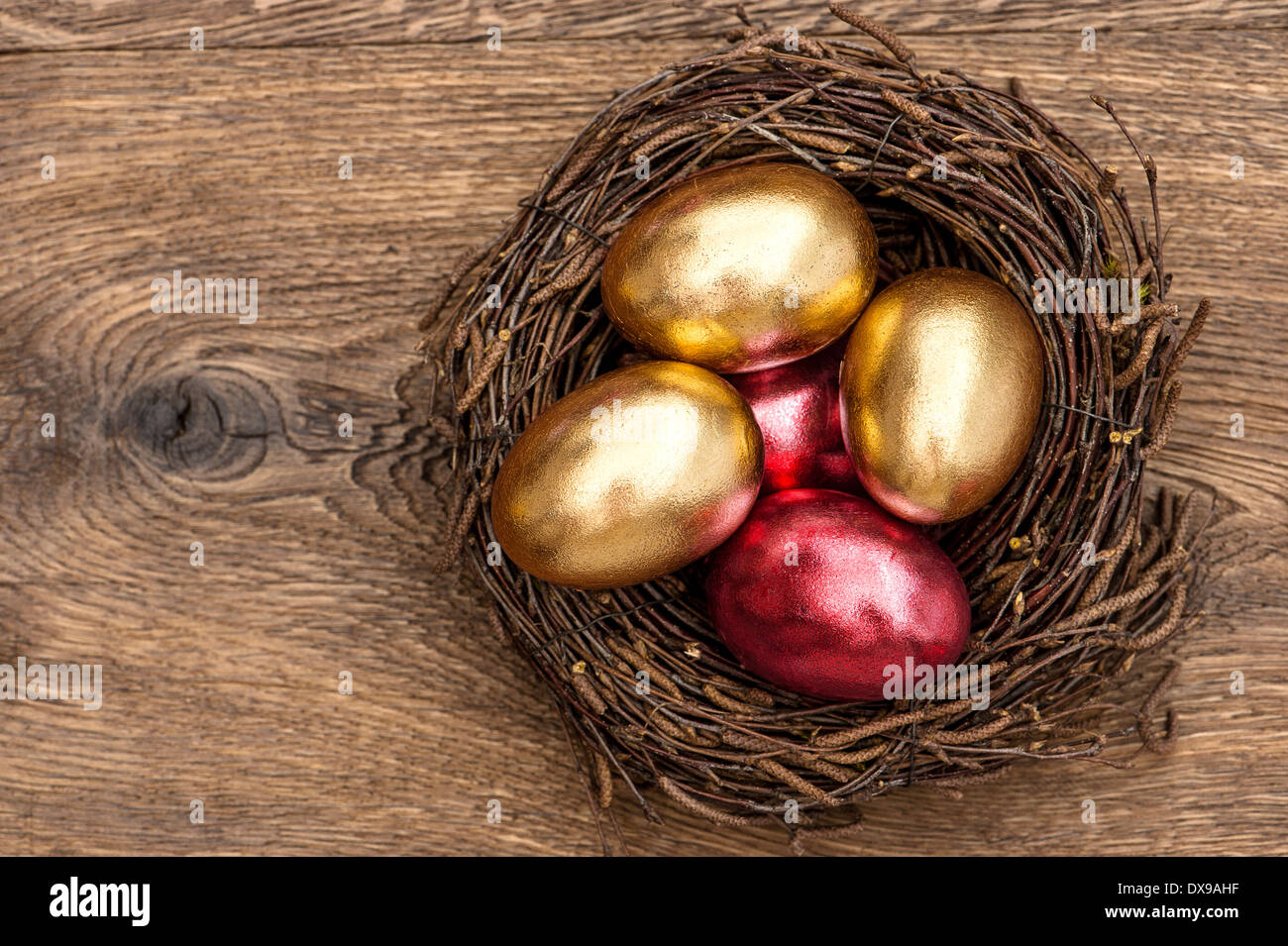 Rouge et Or oeufs de pâques dans son nid sur fond de bois vintage Banque D'Images