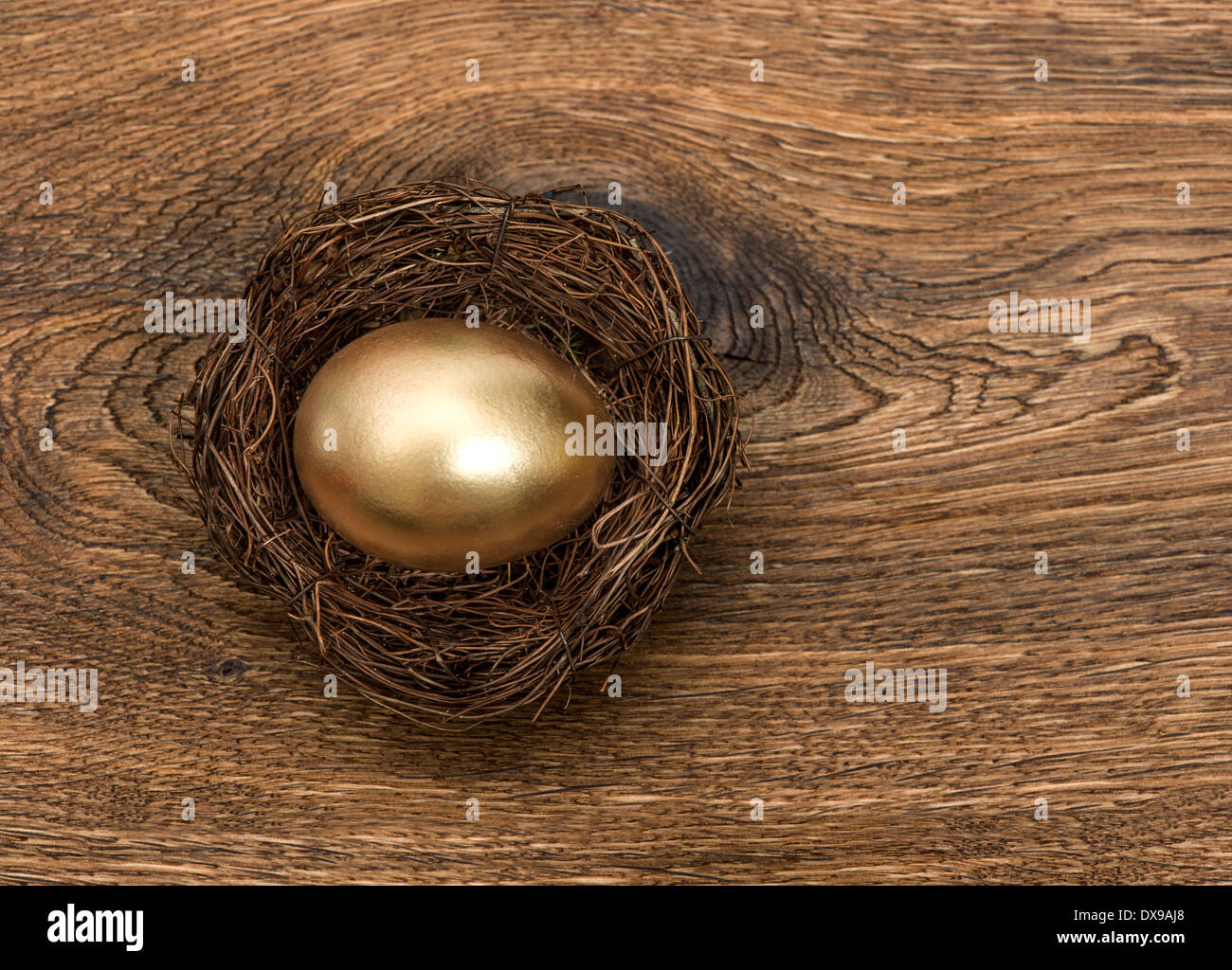 Golden oeuf de Pâques dans oiseaux nichent sur fond de bois vintage Banque D'Images