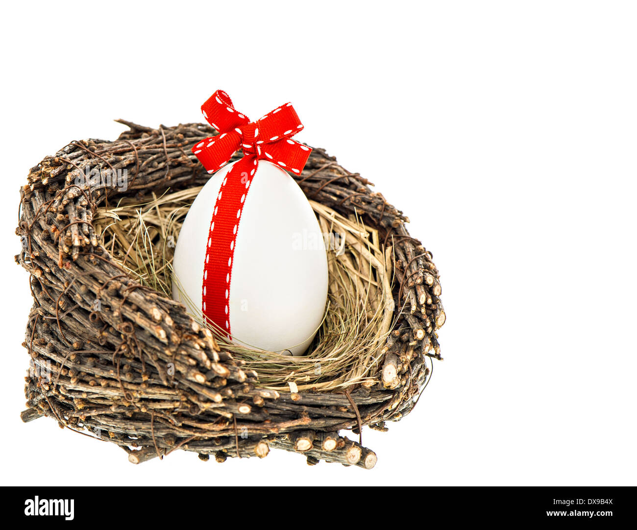Oeuf de Pâques blanc avec ruban rouge décoration bow en nid en bois isolé sur fond blanc Banque D'Images