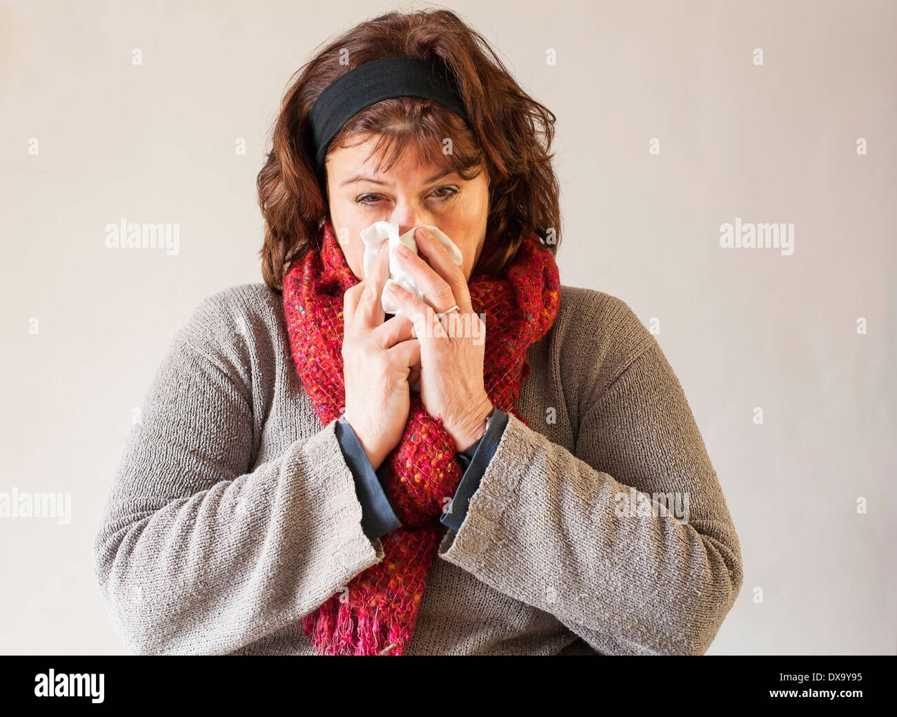 Femme avec écharpe rouge et handkerchieif blowing nose Banque D'Images