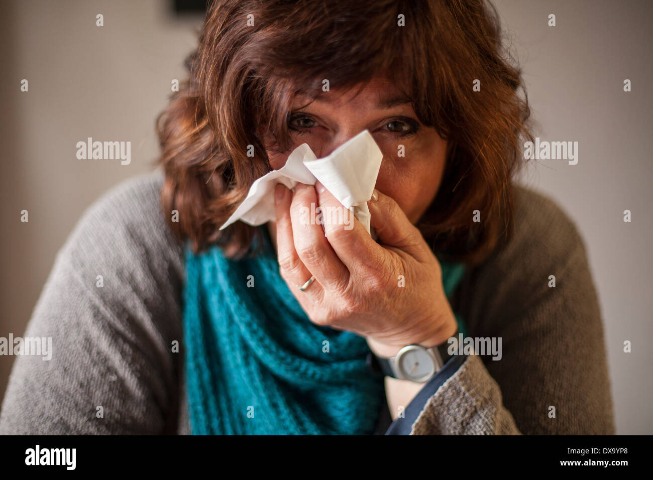 Femme malade avec écharpe bleue et mouchoir blowing nose Banque D'Images