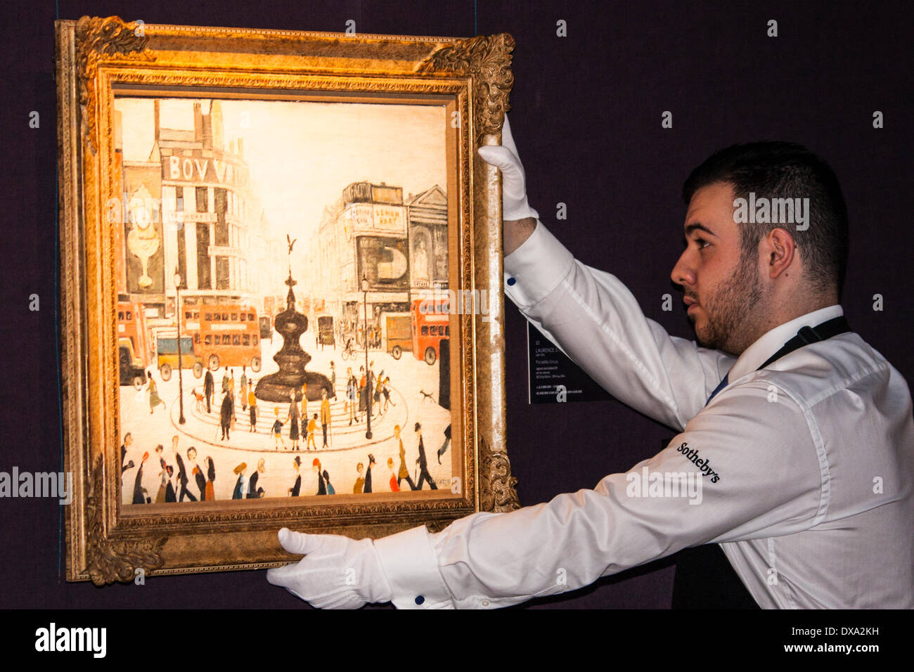 Sotheby's, Londres, Royaume-Uni. Le 21 mars 2014. Un travailleur de Sotheby's est l'un des deux LS Lowry's Piccadilly Circus tableaux comme cela et d'autres de ses oeuvres à partir de l'AJ Thompson Collection sont exposées avant la vente aux enchères où les travaux devraient recueillir plus de £15 millions. Crédit : Paul Davey/Alamy Live News Banque D'Images