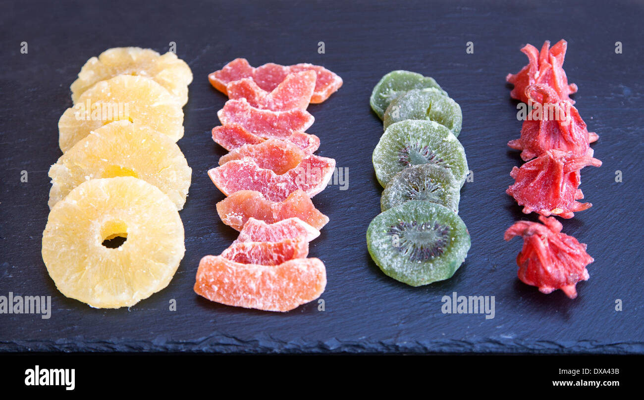Sugared séchés ananas, goyave, kiwi et fleur d'hibiscus sur une plaque en ardoise noire Banque D'Images