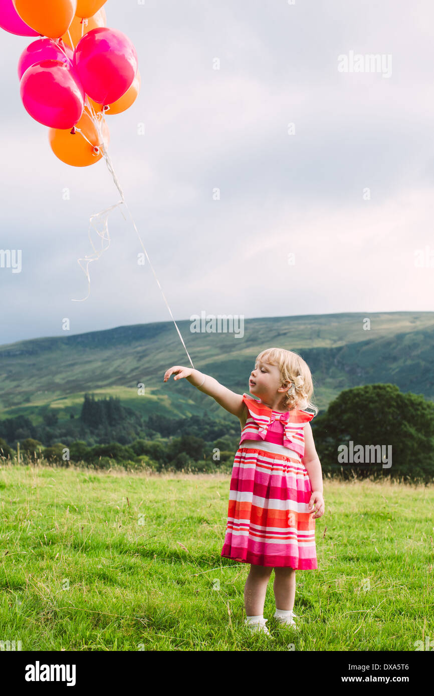 Birthday girl holding red et ballons orange Banque D'Images