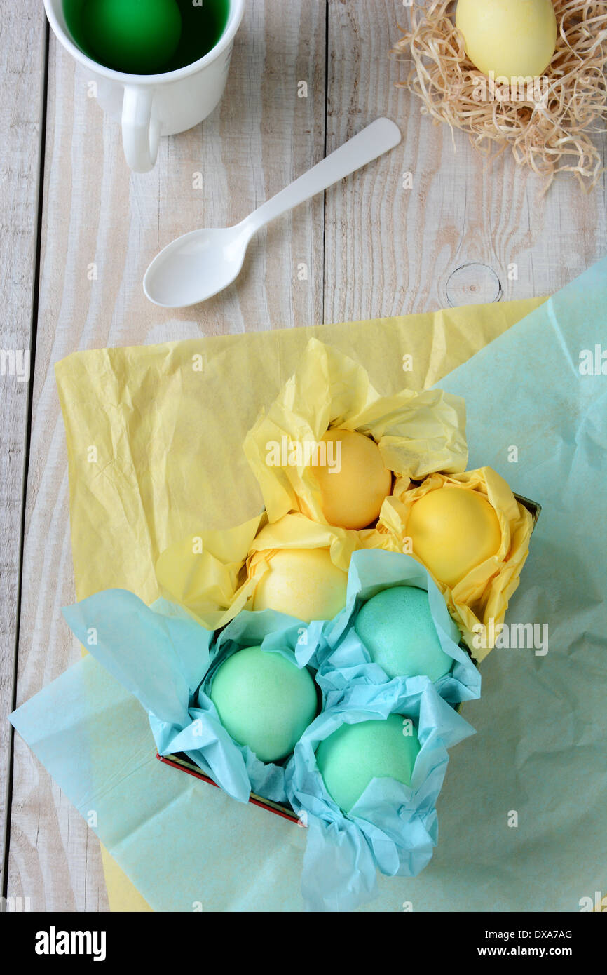 Portrait d'une boîte d'oeufs de Pâques pastel enveloppé de papier de soie. La boîte est sur une table de cuisine de style rustique Banque D'Images