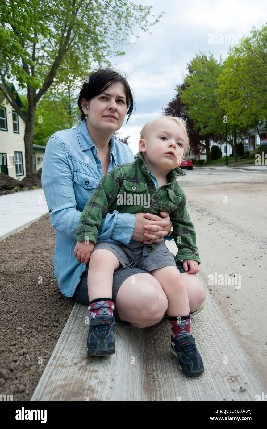 Bébé garçon assis sur les genoux de la mère à l'extérieur au printemps à la recherche dans la rue Banque D'Images