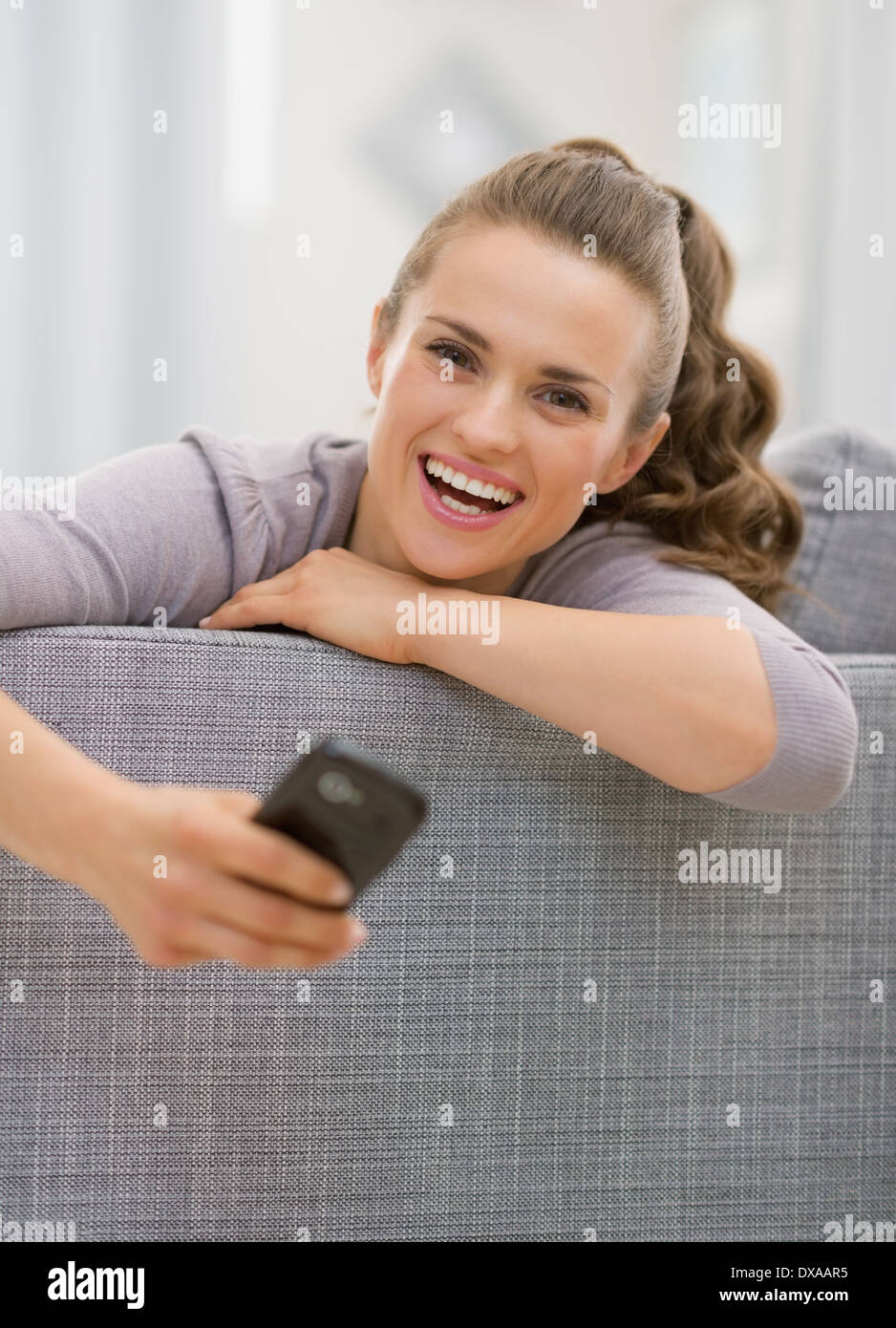 Portrait of young woman laying on sofa with phone Banque D'Images