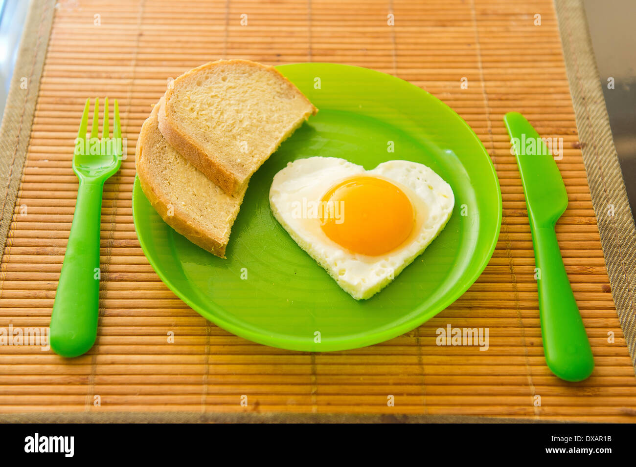 Des oeufs au plat en forme de coeur sur la plaque de plastique vert Banque D'Images