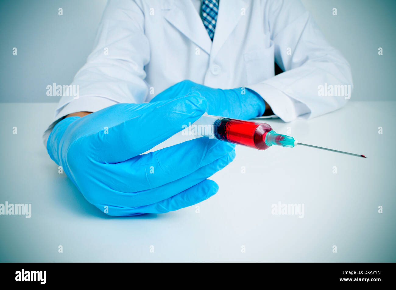 Un médecin portant des gants médicaux tenant une seringue avec du sang Banque D'Images