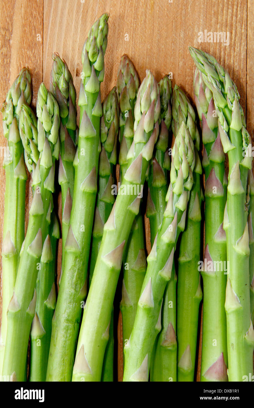 Les pointes d'asperges vertes fraîches/branches contre fond de bois, UK Banque D'Images