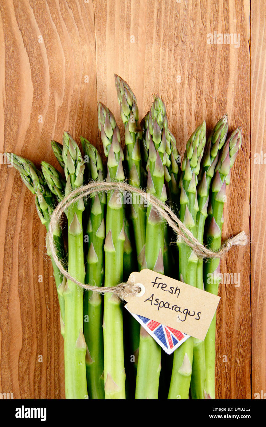Un tas de frais vert asperges avec contre étiquette, rustique en bois vintage background, UK - avec copie espace. Banque D'Images