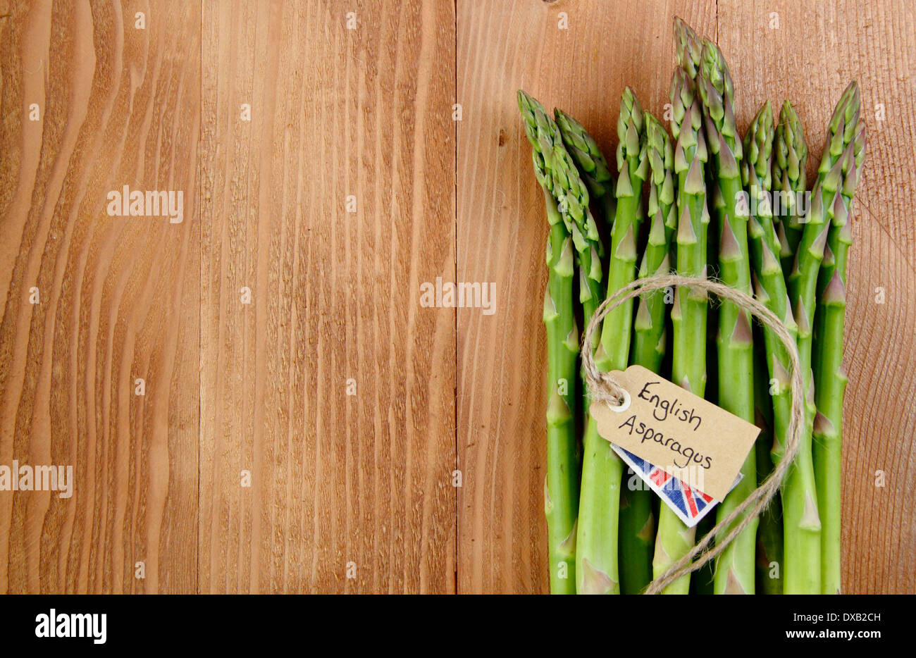 Un tas de frais vert asperges avec contre étiquette, rustique en bois vintage background, UK - avec copie espace. Banque D'Images