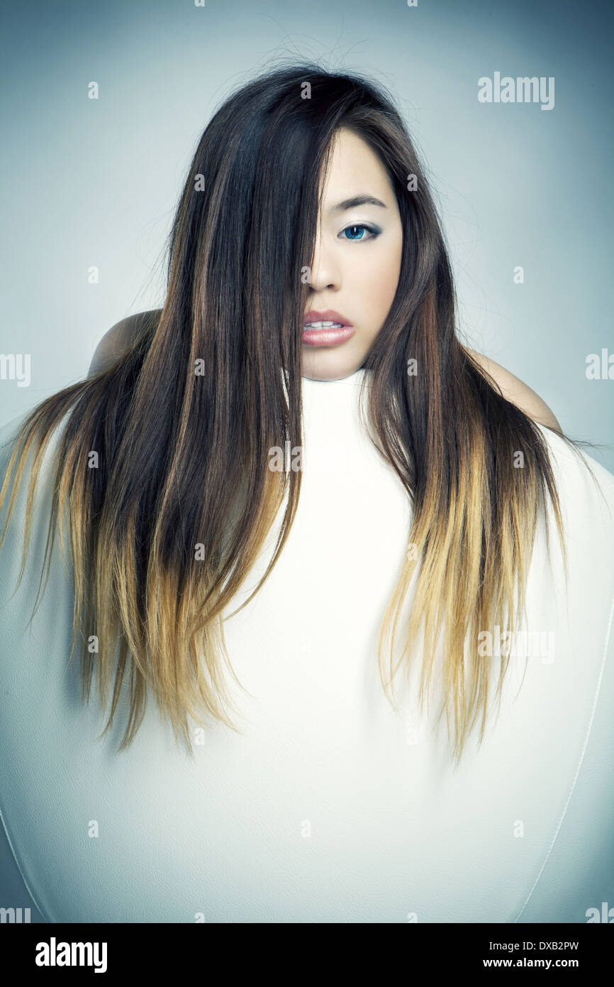 Jeune fille asiatique avec des yeux bleus dans la chaise blanche Banque D'Images