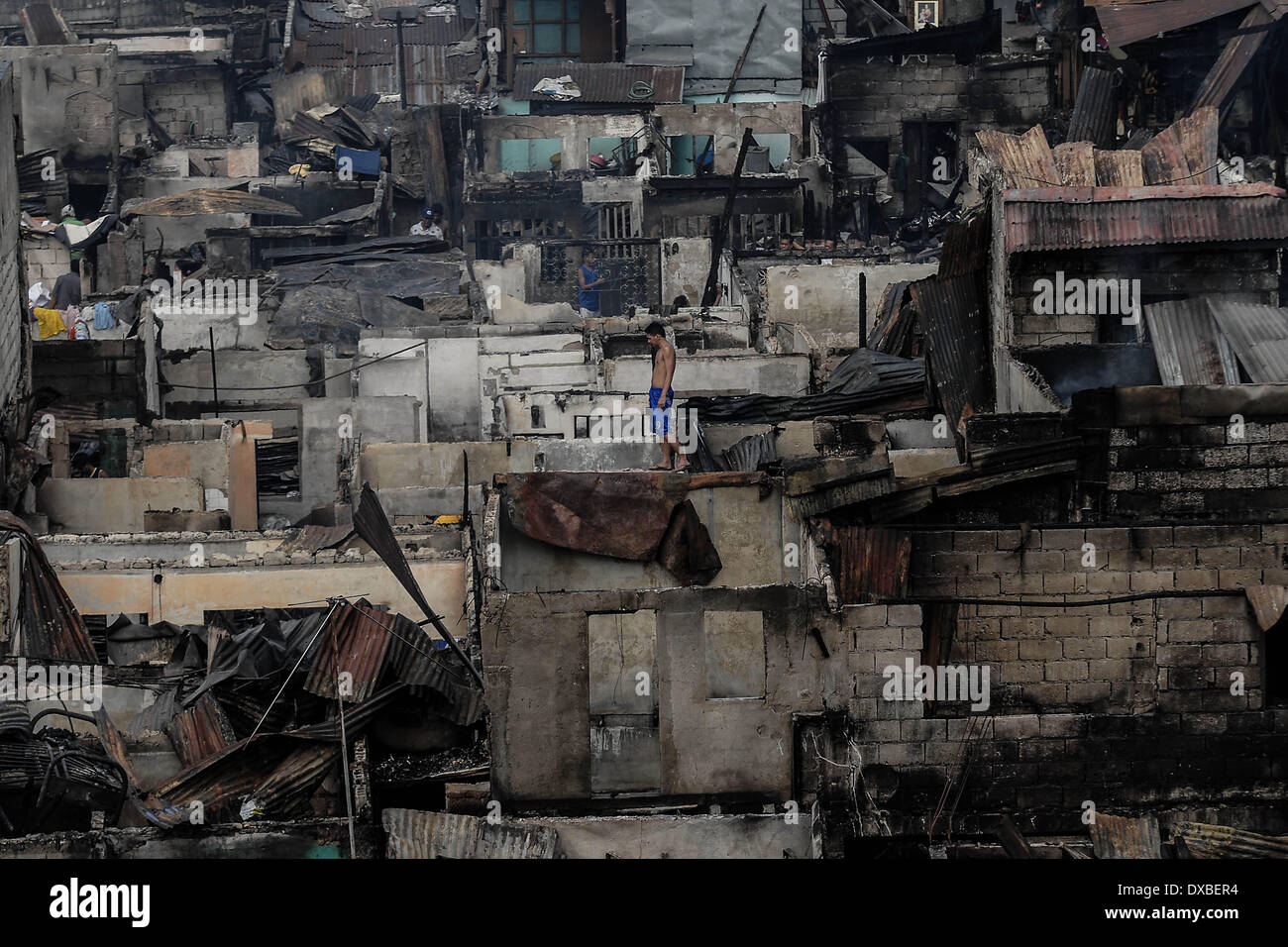 Caloocan (Philippines). Mar 23, 2014. Promenades au milieu d'un résident des rangées de maisons brûlées après un incendie détruit une zone résidentielle à Caloocan City, au nord de Manille, Philippines, le 23 mars 2014. Au moins 1700 familles ont été laissées sans abri après 3 feux distincts vidé de 700 maisons dans une période de 24 heures. Les incendies ont eu lieu comme le pays observe le mois de la prévention des incendies.Photo : Ezra Acayan/NurPhoto Acayan Crédit : Ezra/NurPhoto ZUMAPRESS.com/Alamy/Live News Banque D'Images