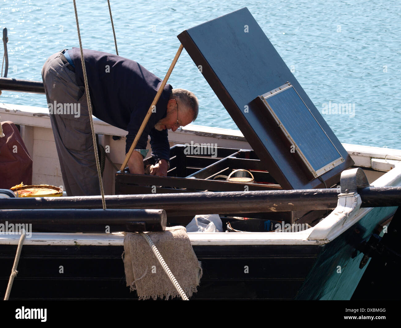 L'homme travaillant sur le moteur de bateau traditionnel en bois, Penzance, Cornwall, UK Banque D'Images