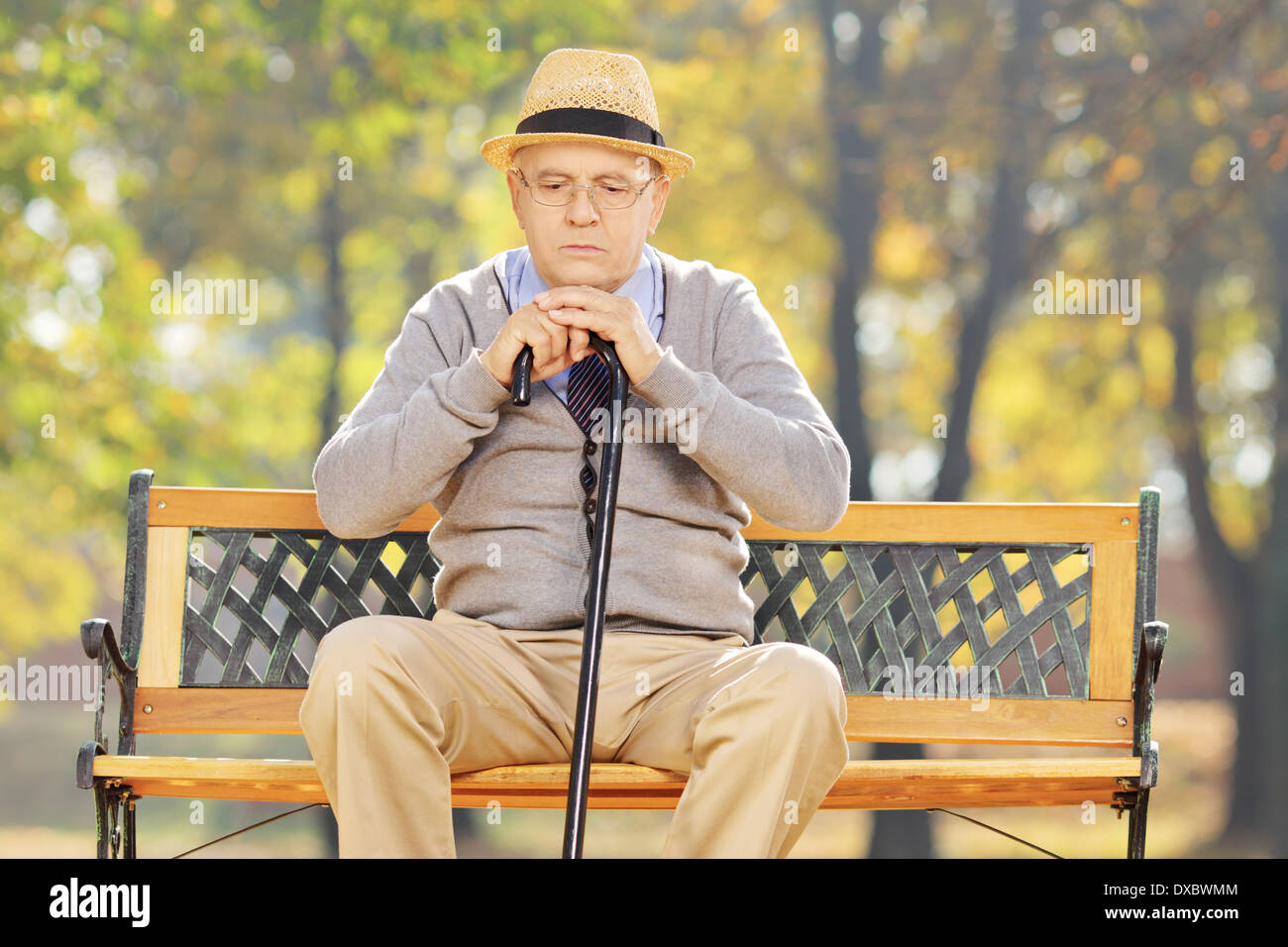 Happy man avec une canne assis sur un banc dans un parc Banque D'Images