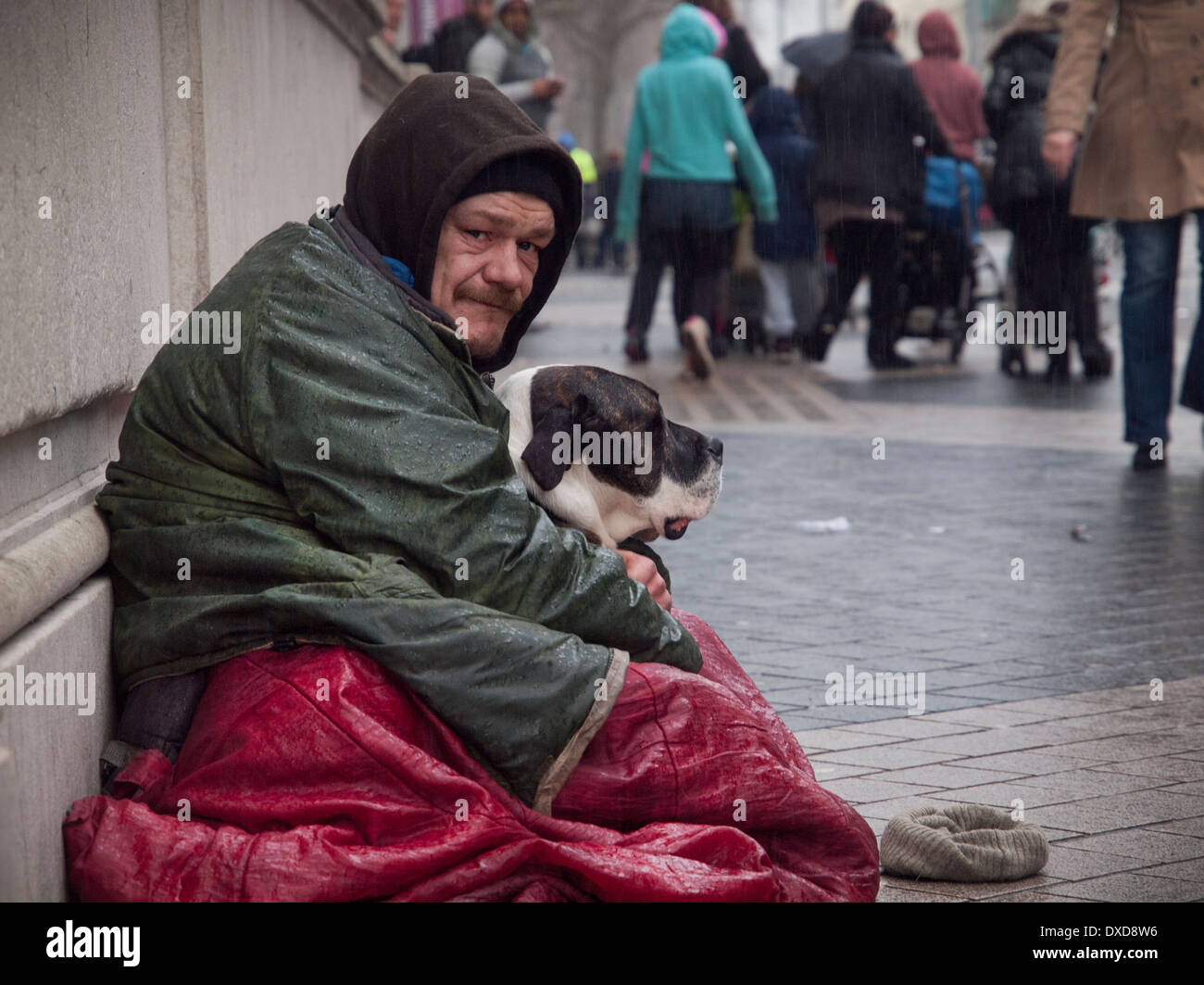 Un sans-abri se trouve dans la pluie avec son chien à Londres Banque D'Images