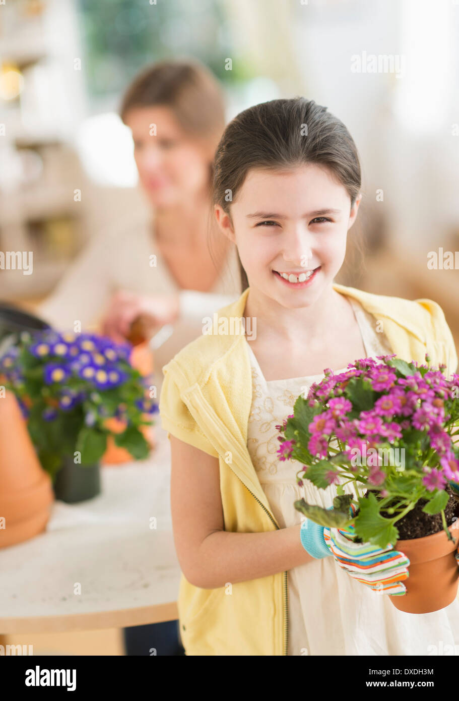 Girl (8-9) et la mère de fleurs en pot Banque D'Images