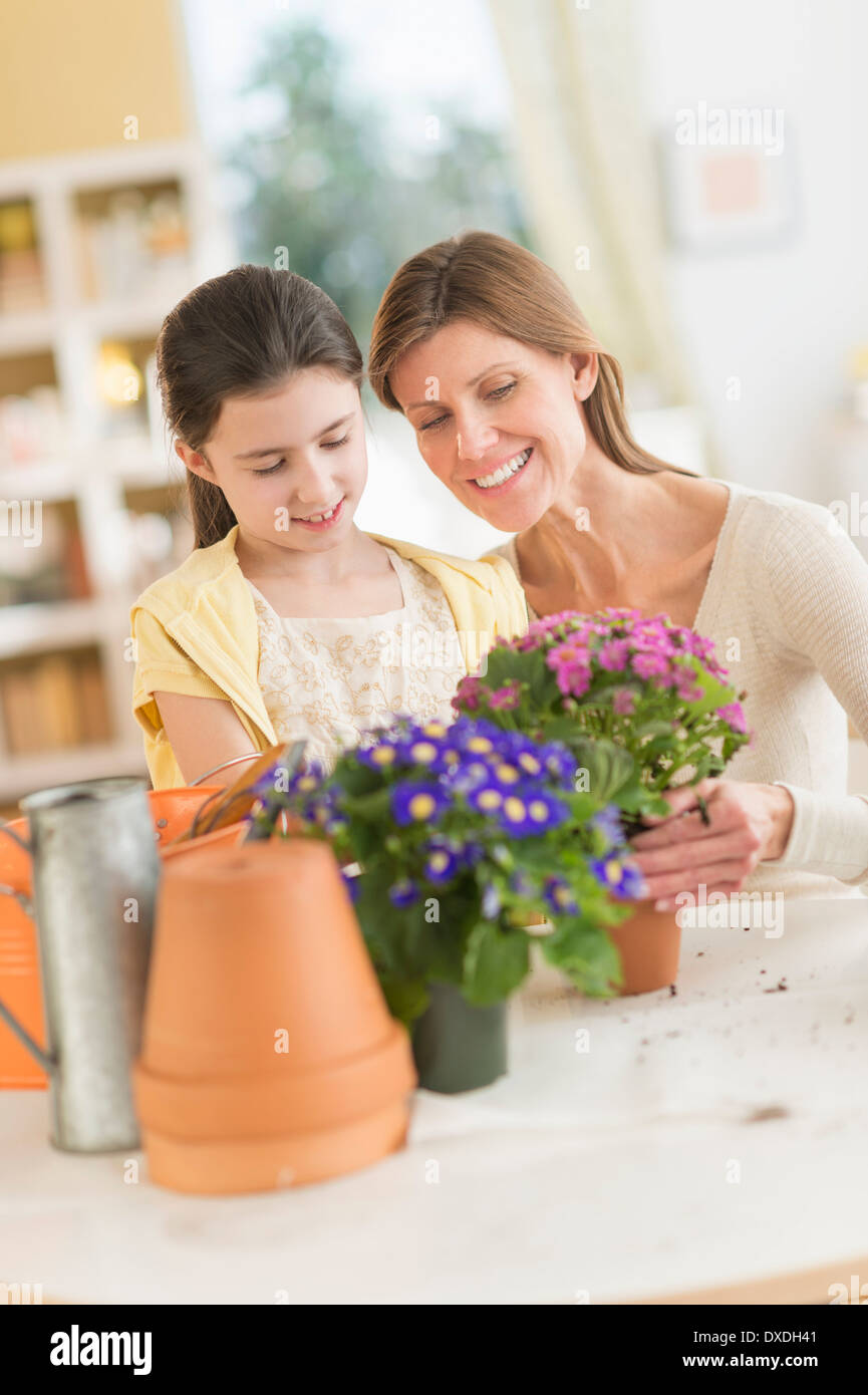 Girl (8-9) et la mère de fleurs en pot Banque D'Images