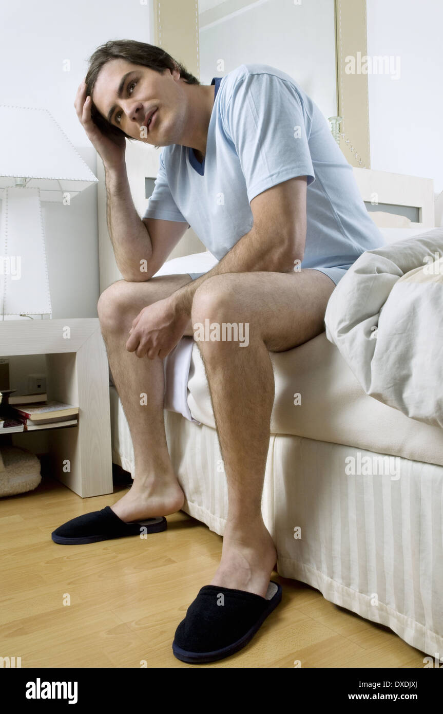 Jeune homme en chaussons sitting on bed Photo Stock - Alamy
