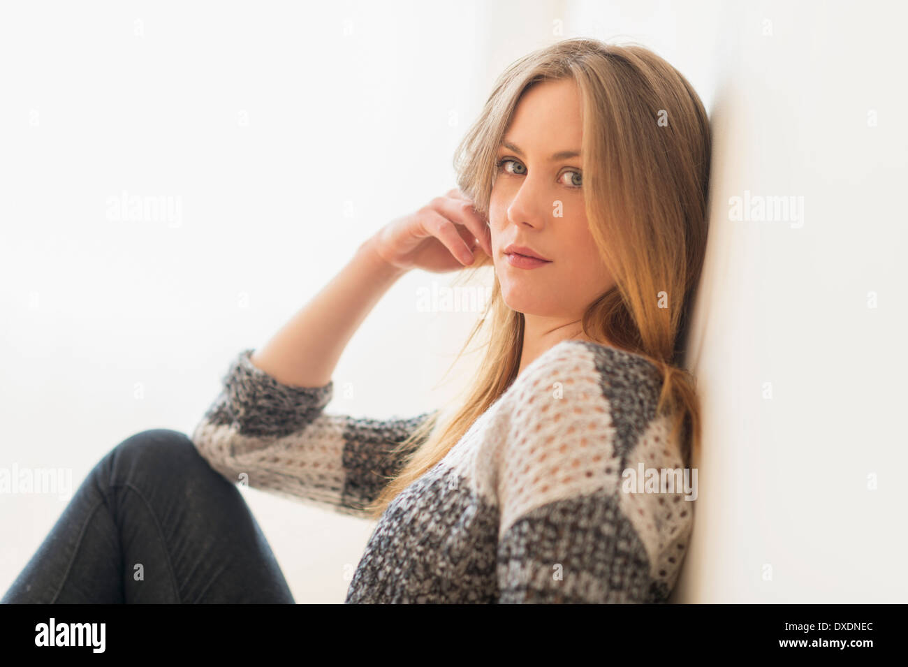 Portrait of attractive young woman sitting by wall Banque D'Images
