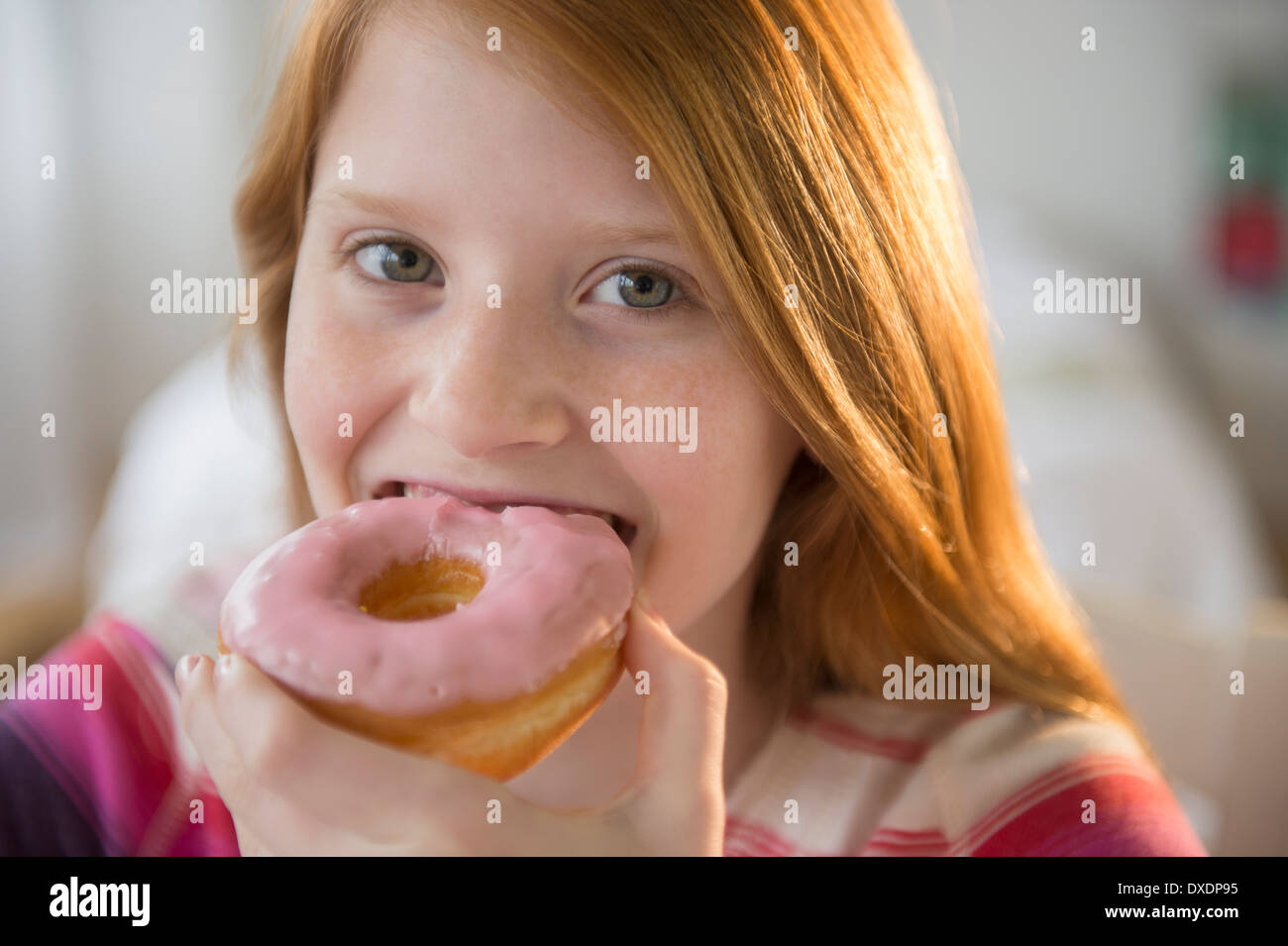 Portrait of Girl (12-13) eating donut Banque D'Images