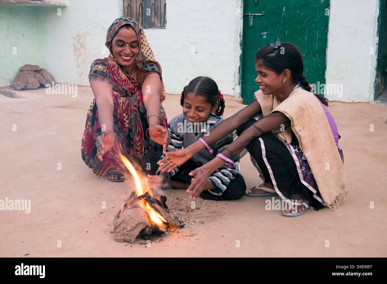 L'Inde, Uttar Pradesh, Agra, femme et deux filles réchauffement climatique les mains à côté d'un petit incendie alimenté par de la bouse de vache et de bambou Banque D'Images