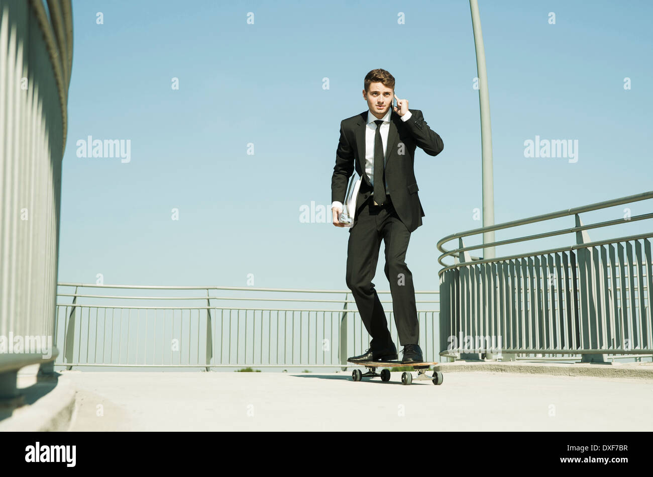 Businessman using Cell Phone while Skateboarding, Mannheim, Baden-Wurttemberg, Germany Banque D'Images