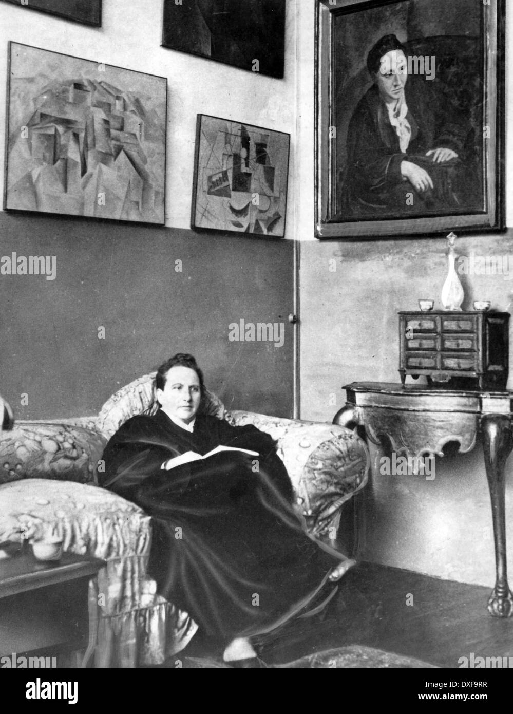 GERTRUDE STEIN (1874-1946) écrivain américain à New York en 1935 avec son portrait par Picasso sur le mur Banque D'Images
