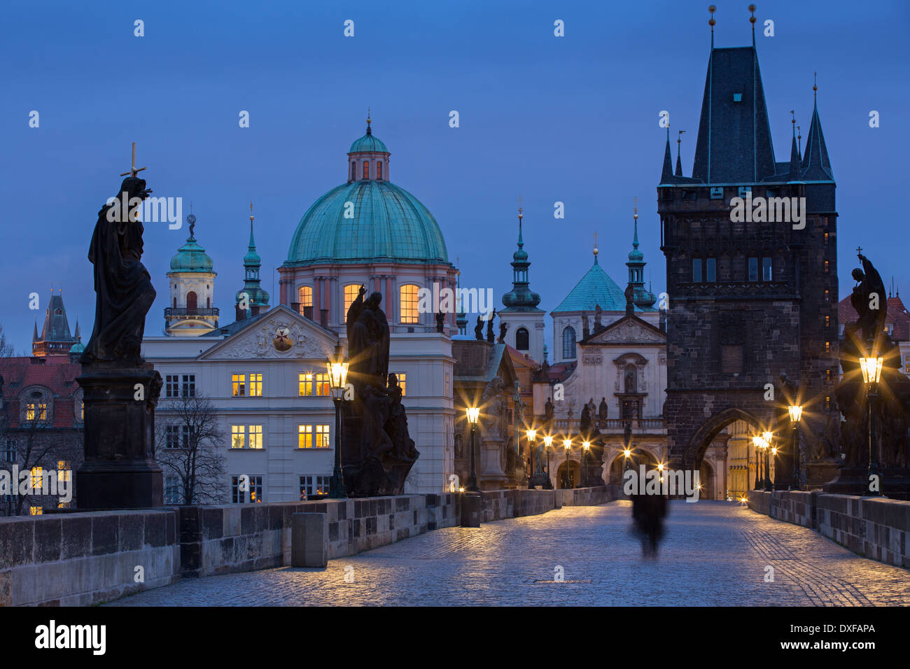 Une figure solitaire sur le pont Charles à l'aube avec les tours et les clochers de la vieille ville, au-delà de Prague, République Tchèque Banque D'Images