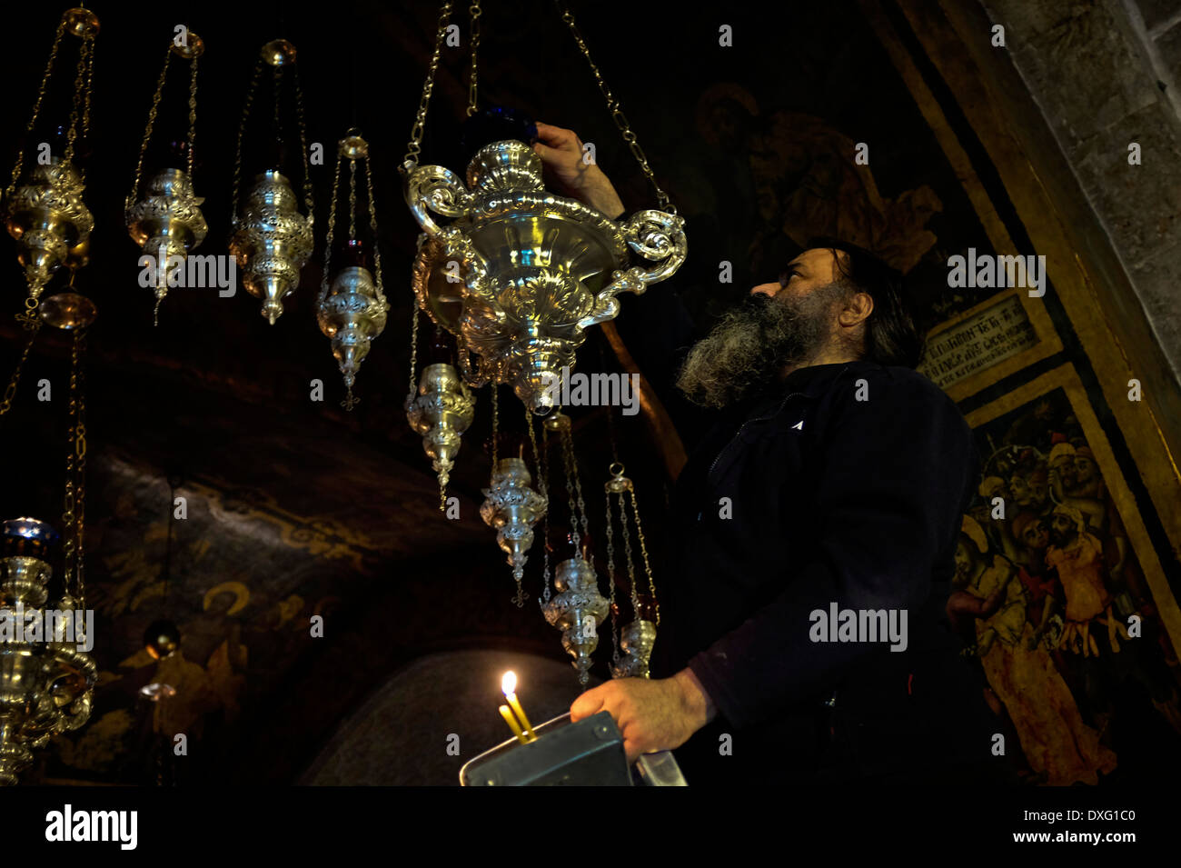 Un dignitaire religieux orthodoxe grec d'ajouter de l'huile à feux à l'église de Saint Sépulcre, dans la vieille ville de Jérusalem Israël Banque D'Images