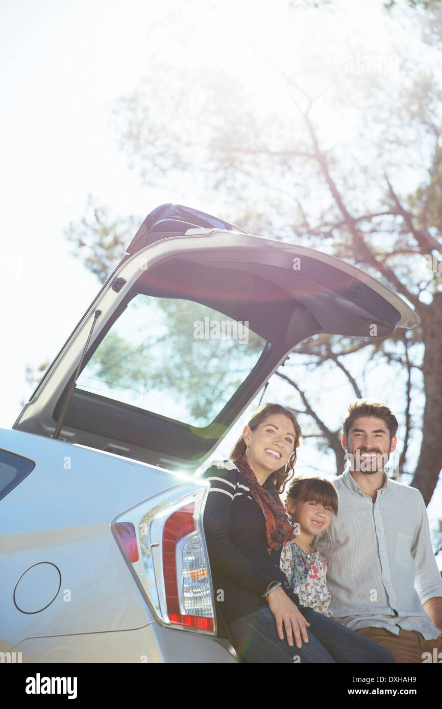 Portrait of smiling family sitting contre l'arrière de la voiture Banque D'Images
