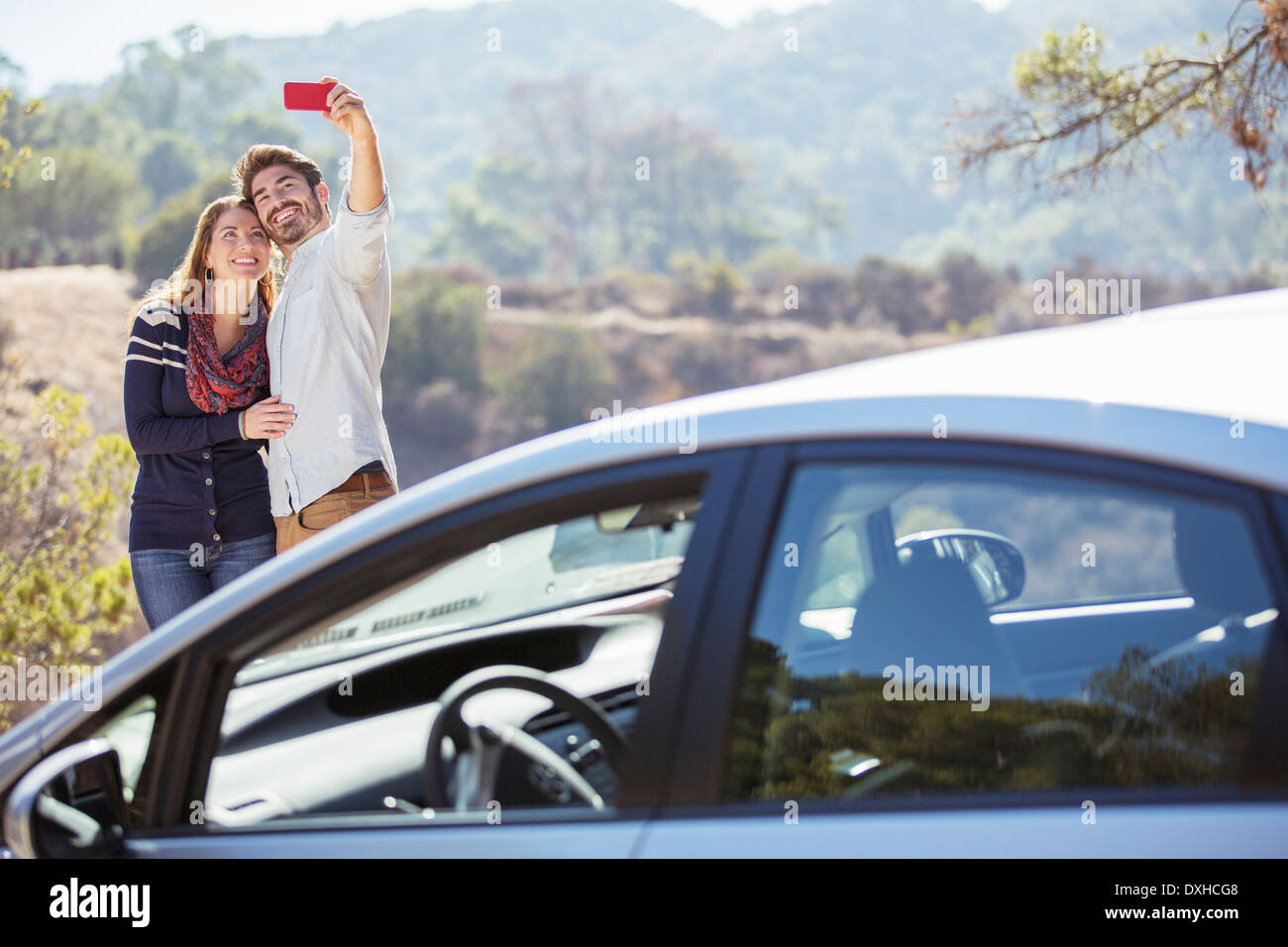 Couple taking self-portrait with cell phone parking extérieur Banque D'Images