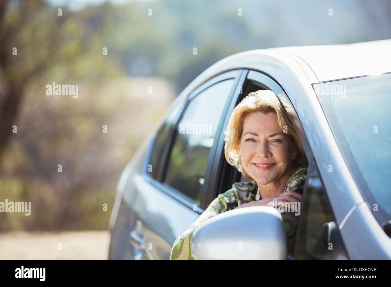 Portrait of smiling senior woman leaning out car window Banque D'Images