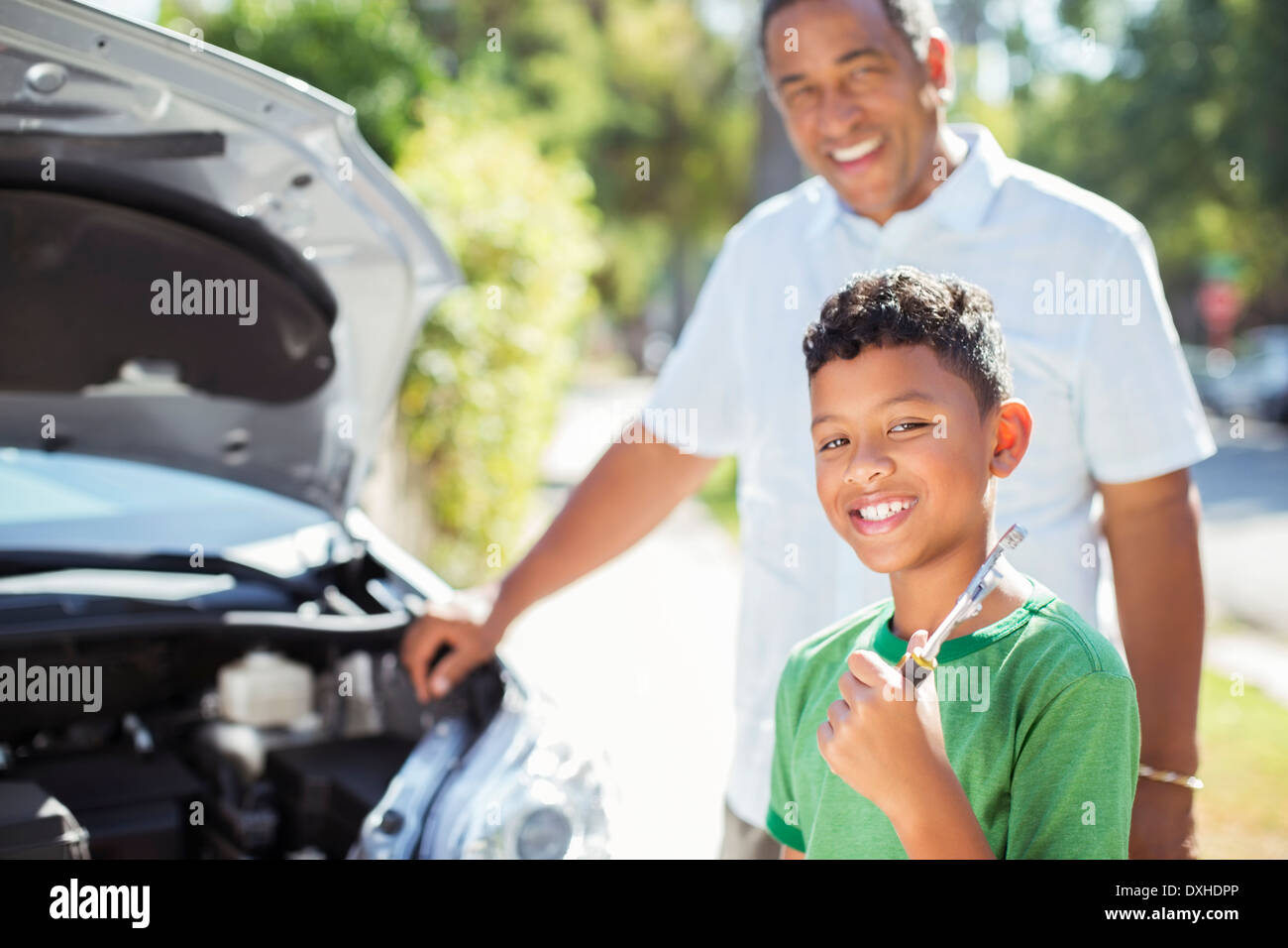 Portrait of smiling petit-fils la réparation de moteur de voiture avec son grand-père Banque D'Images