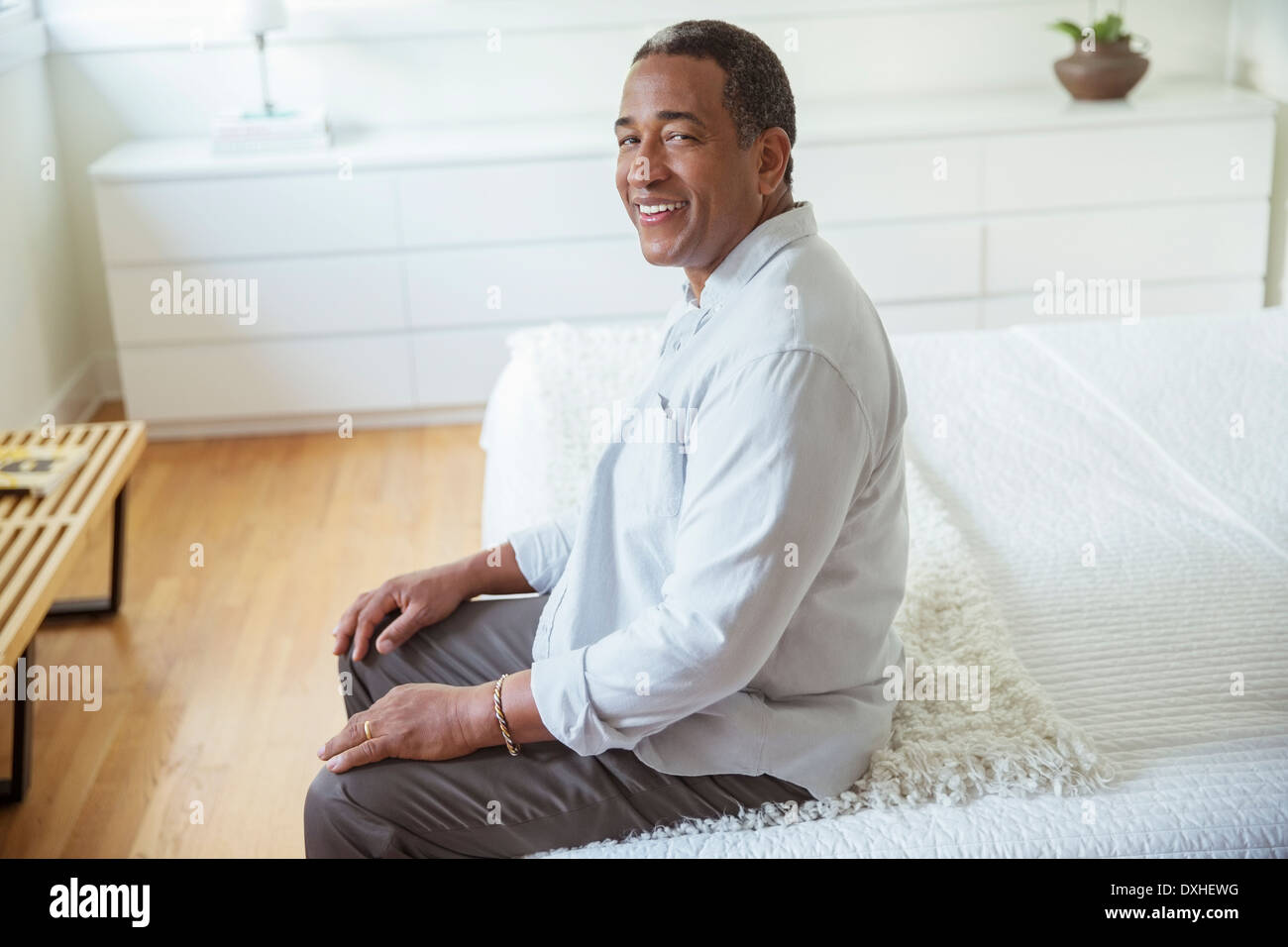 Portrait of smiling senior homme assis au bord du lit Banque D'Images
