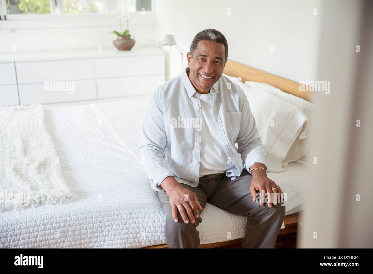 Portrait of smiling senior woman sitting on bed Banque D'Images