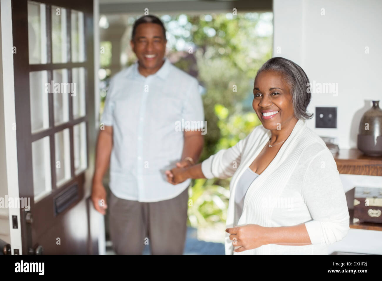 Portrait of smiling senior couple holding hands in doorway Banque D'Images