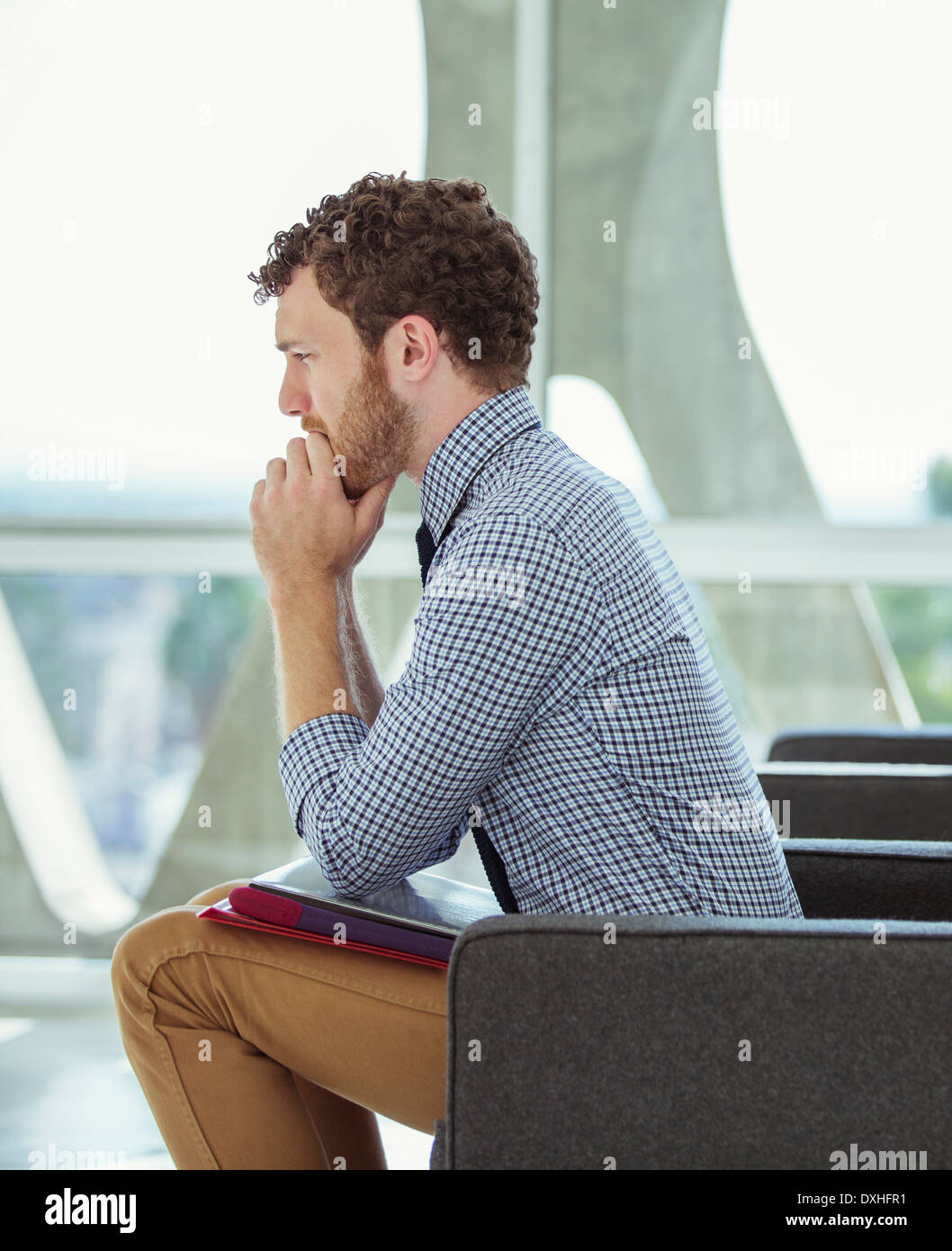 Pensive businessman sitting in office lobby Banque D'Images