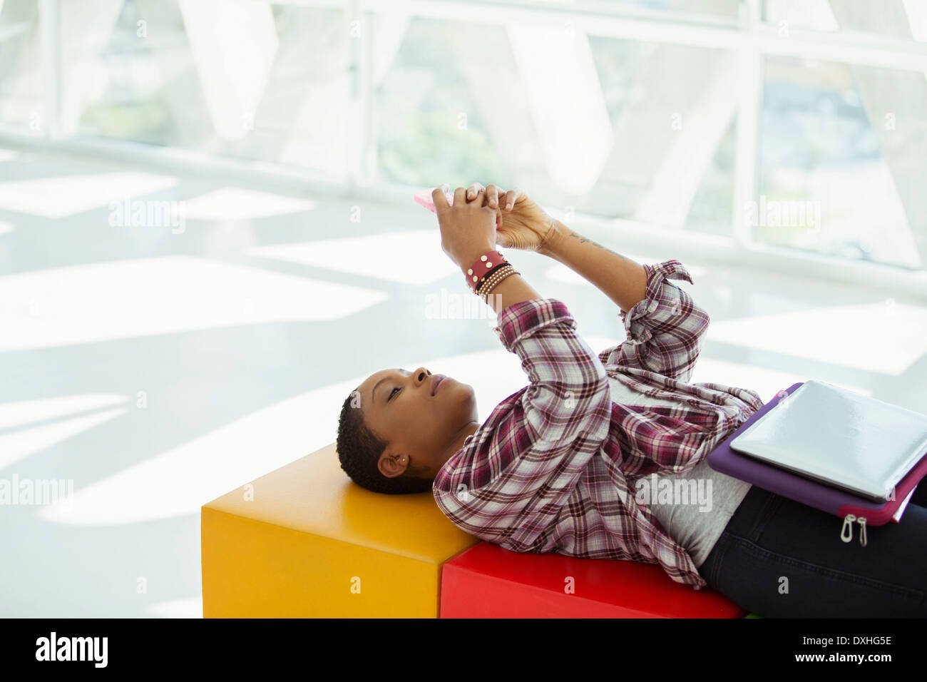 Femme d'occasionnels portant sur l'établi et de messagerie texte avec cell phone Banque D'Images