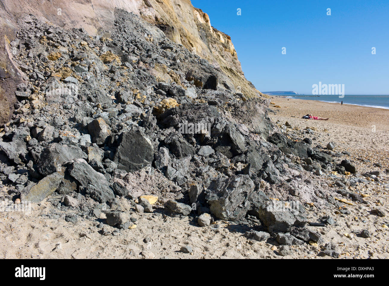 Baigneurs sur la plage dangereusement près de la chute de roches de l'érosion des falaises à Hengistbury Head, Dorset, UK Banque D'Images