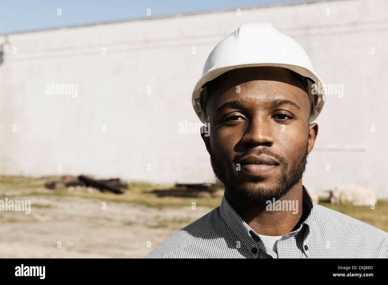 Portrait d'homme noir wearing hard-hat at construction site Banque D'Images