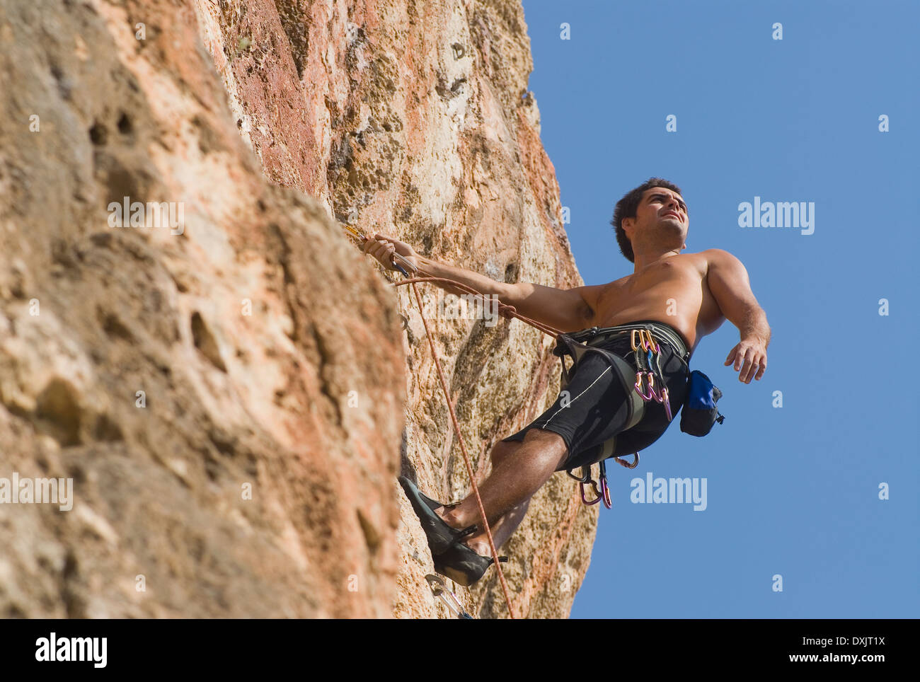 Male rock climber scaling rock face sécurisé par des cordes low angle view Banque D'Images