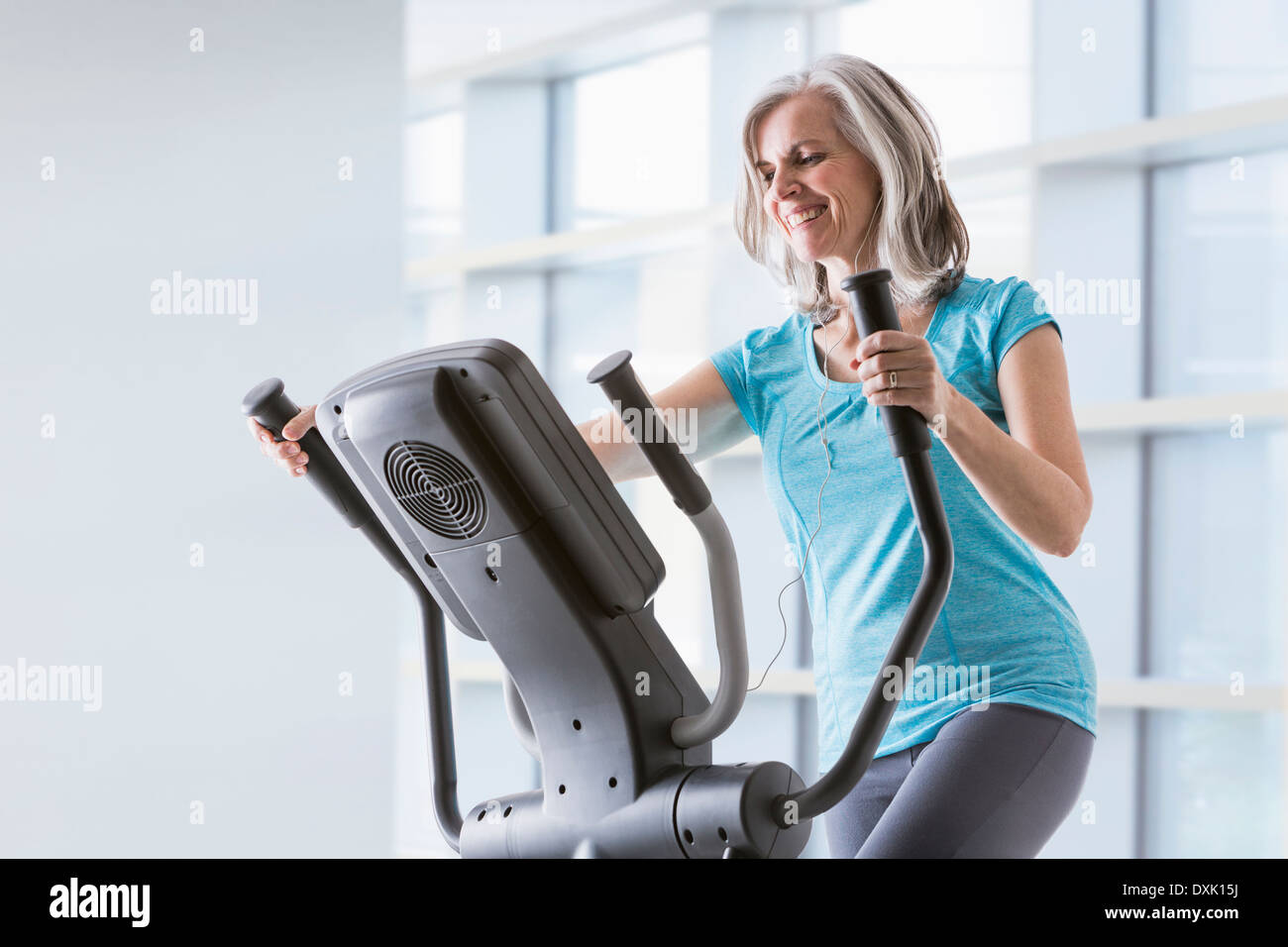 Happy Caucasian woman on elliptical trainer at gym Banque D'Images