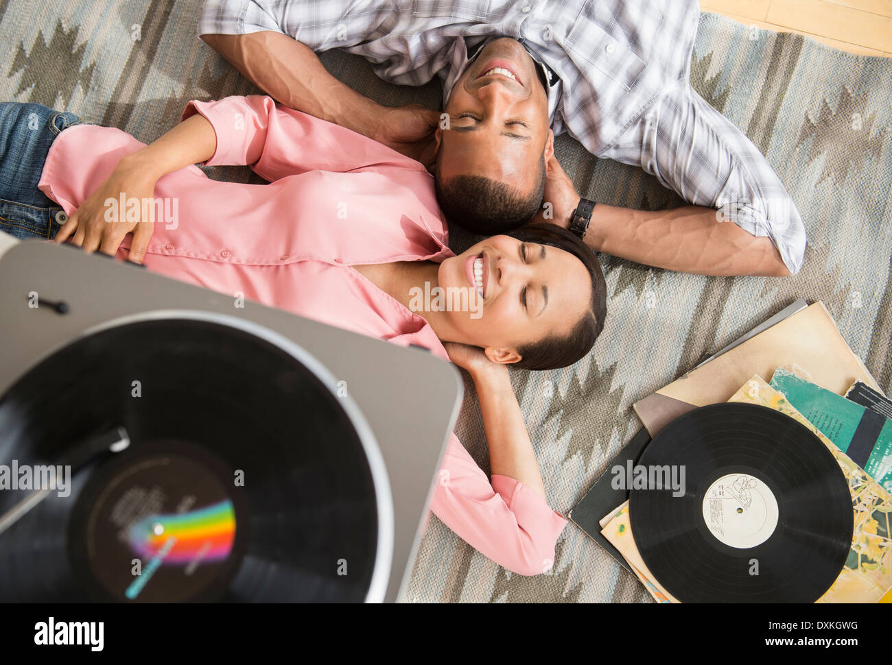 Couple heureux sur un tapis à l'écoute de record player Banque D'Images