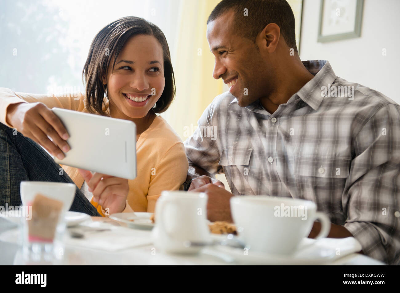Heureux couple drinking coffee and using digital tablet Banque D'Images