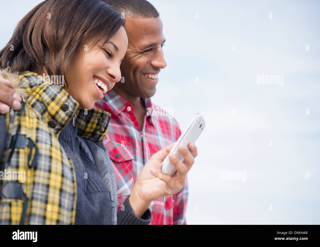 Happy couple using cell phone outdoors Banque D'Images