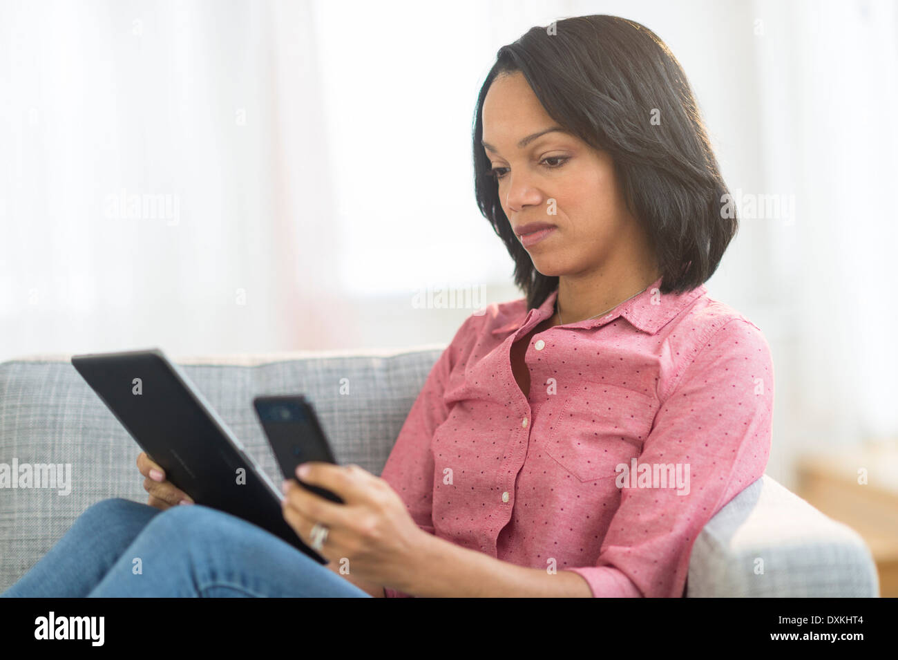 African American Woman using cell phone and digital tablet Banque D'Images
