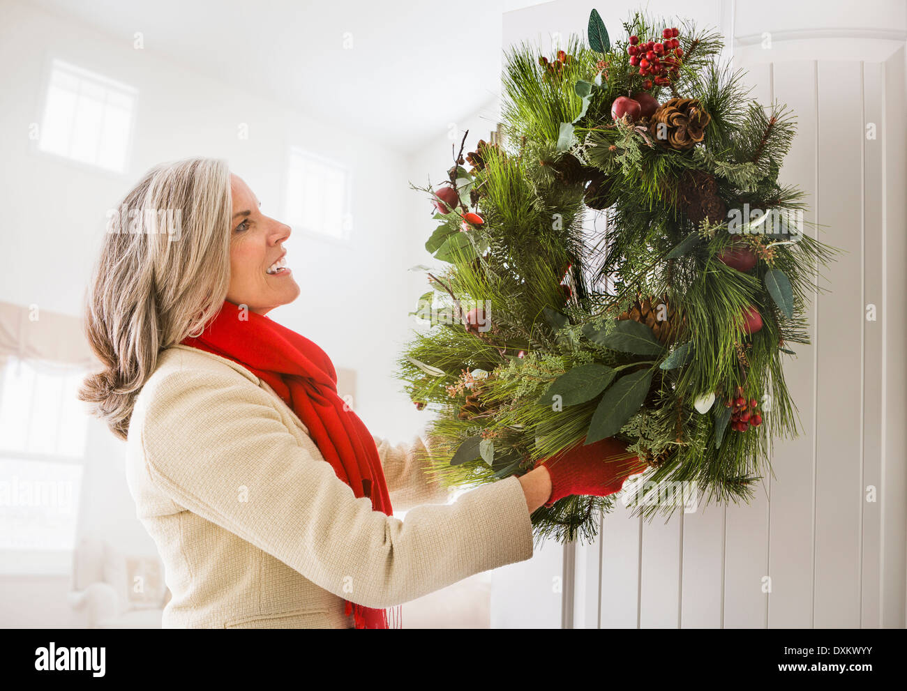 Caucasian woman hanging couronne de Noël sur la porte Banque D'Images