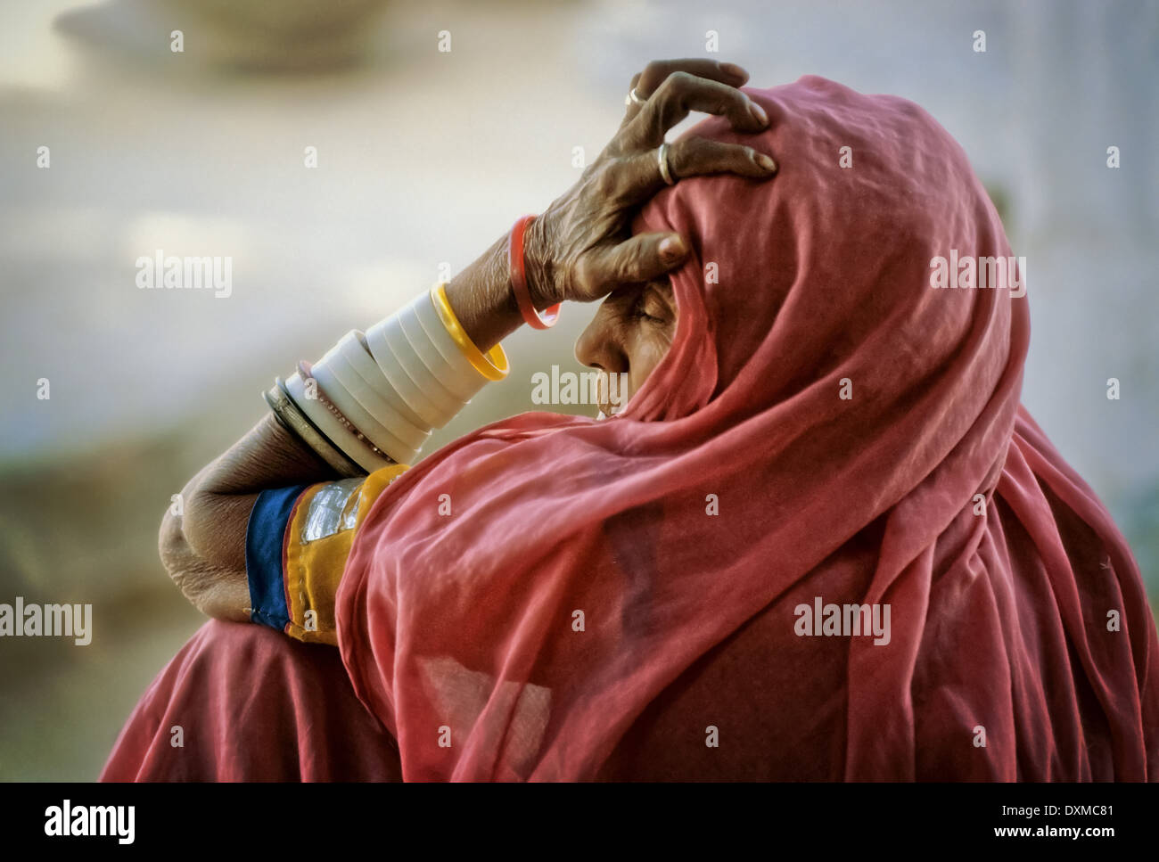 Vieille Femme avec une expression de lassitude portant un foulard rose et plusieurs bracelets de bras dans un village près de Jodhpur, Inde Banque D'Images